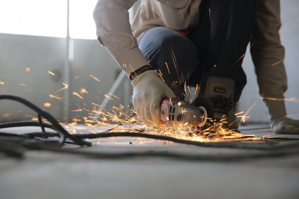 pexels photo 1216544 A skilled industrial worker uses a grinder creating a burst of sparks indoors.